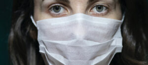 woman wearing surgical mask graphic for article covid loss of income